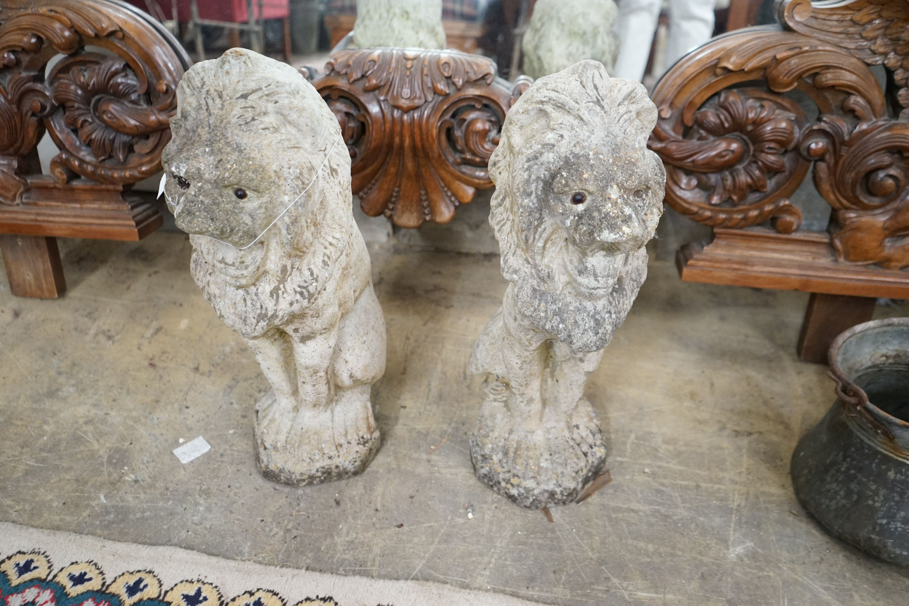 A pair of reconstituted stone seated lion garden ornaments, height 50cm